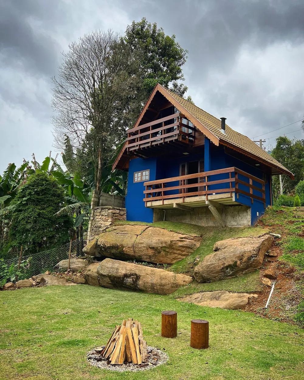 Fachada azul do Chalé Vista da Pedra durante o dia, construído sobre rochas